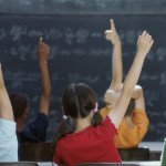 Rear view of class raising hands